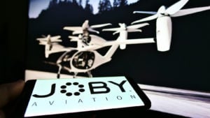 JOBY 주식 화면에 스타트업 및 항공우주 회사 Joby Aviation(에어택시)의 로고가 있는 스마트폰을 들고 있는 사람.