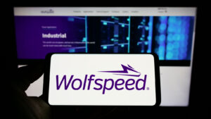 WOLF 주식: 웹 사이트 앞 화면에 미국 반도체 회사인 Wolfspeed Inc.의 로고가 표시된 스마트폰을 들고 있는 사람. 전화 디스플레이에 중점을 둡니다.