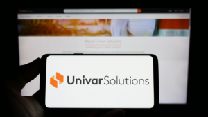 웹사이트 앞 화면에 미국 유통업체 Univar Solutions Inc.(UNVR) 로고가 표시된 스마트폰을 들고 있는 사람. 전화 디스플레이에 중점을 둡니다. 수정되지 않은 사진.